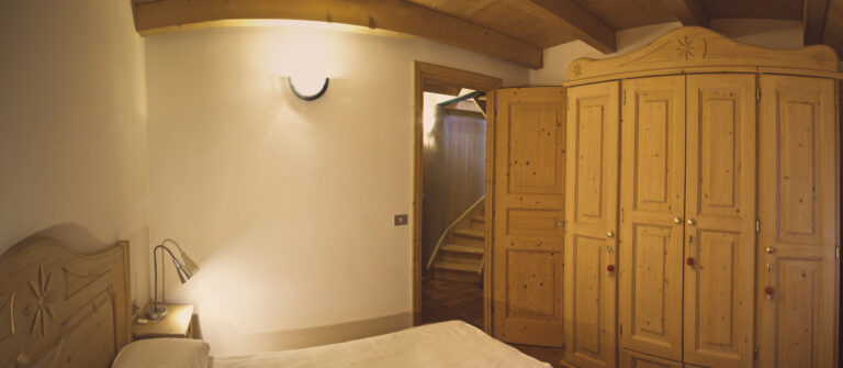 camera da letto in legno e in puro stile alpino con travi a vista